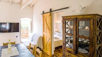 A room with a wooden dining table, chairs, a TV mounted on the wall, a sliding barn door, and a cabinet with glass doors.