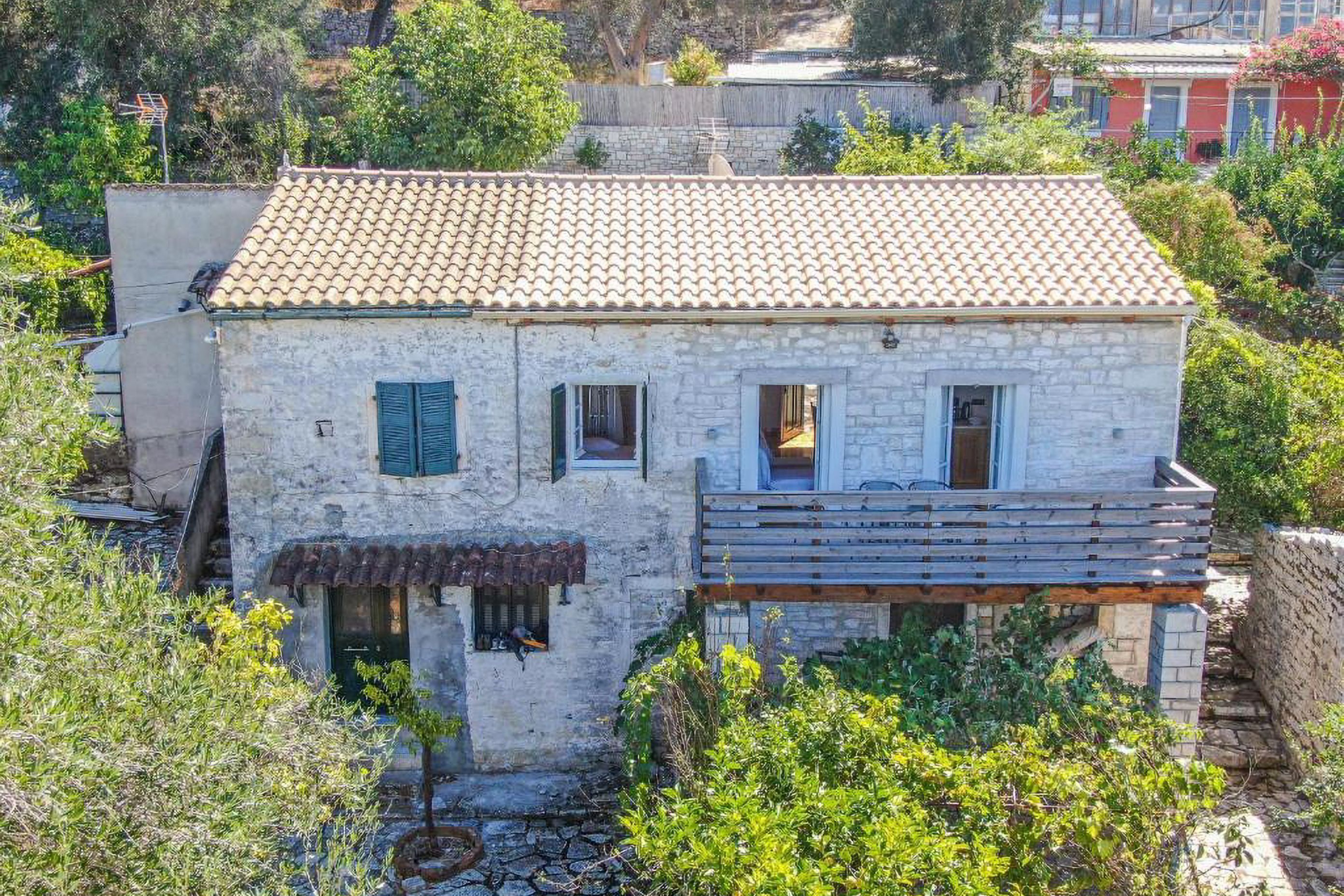 Una casa de piedra con techo de tejas, un pequeño porche y un jardín.