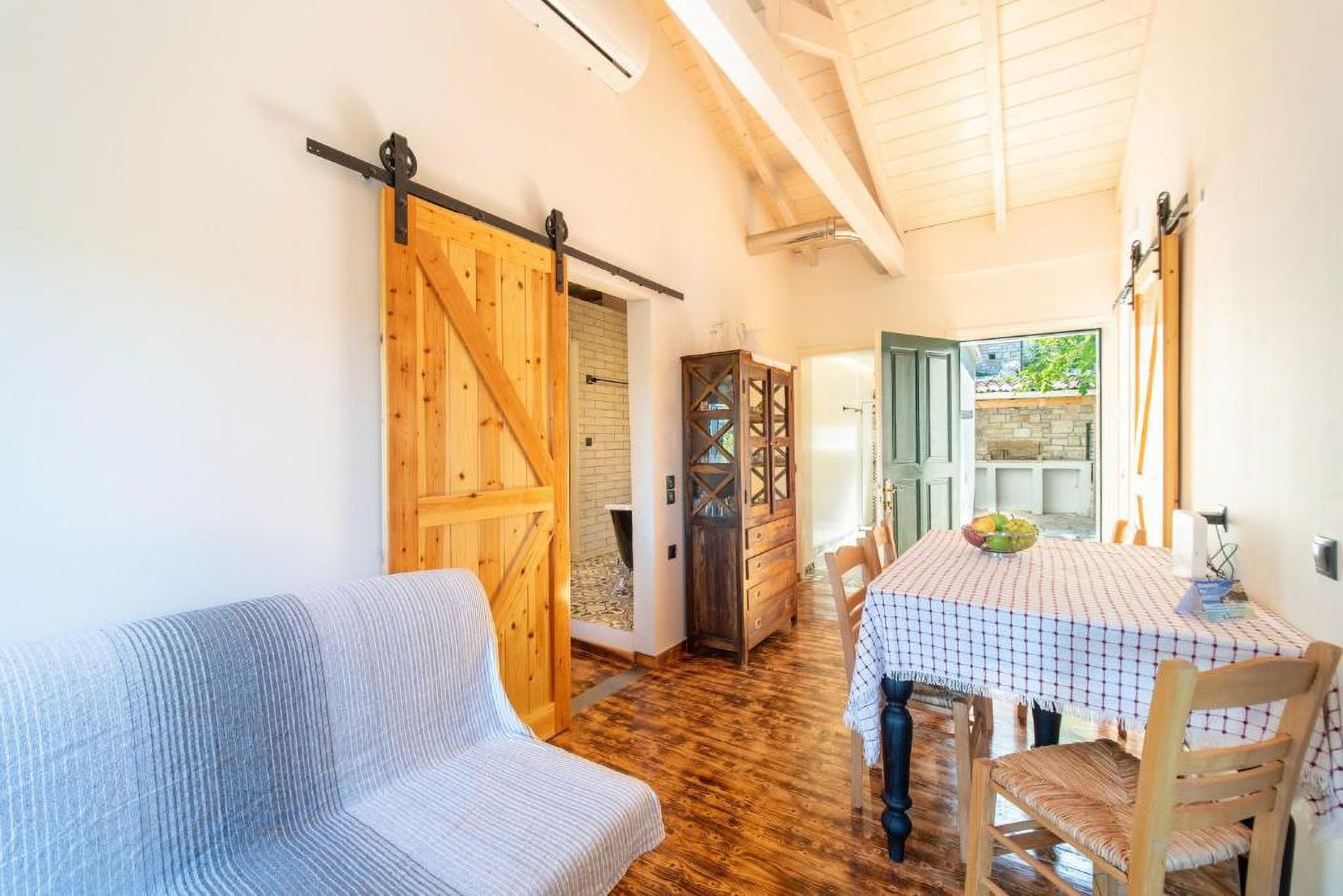 Une pièce chaleureuse avec un plancher en bois, une porte coulissante de style grange, une table à manger avec des chaises et un canapé.