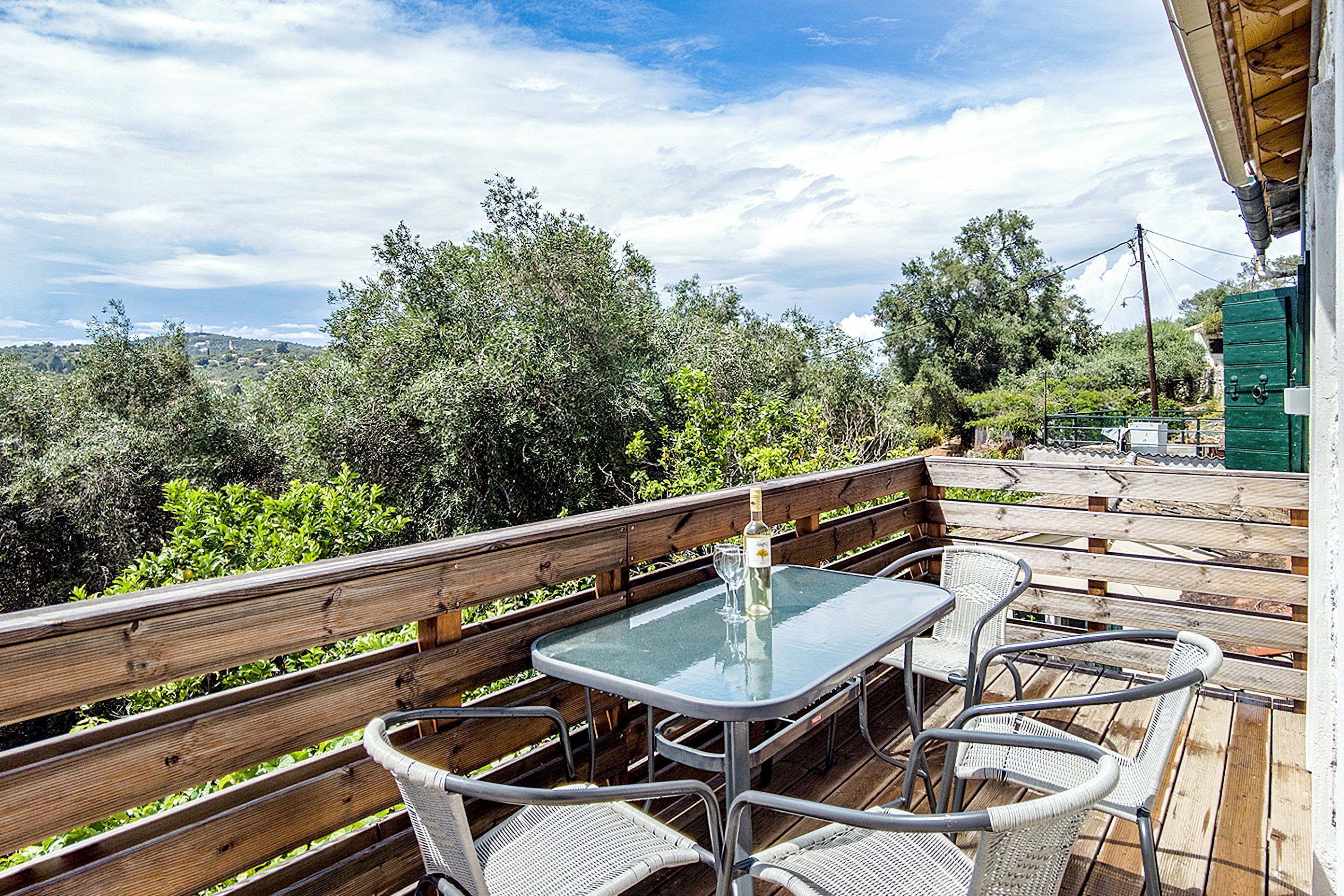 Un patio al aire libre con una mesa de vidrio y sillas de mimbre, con vistas a un paisaje exuberante.