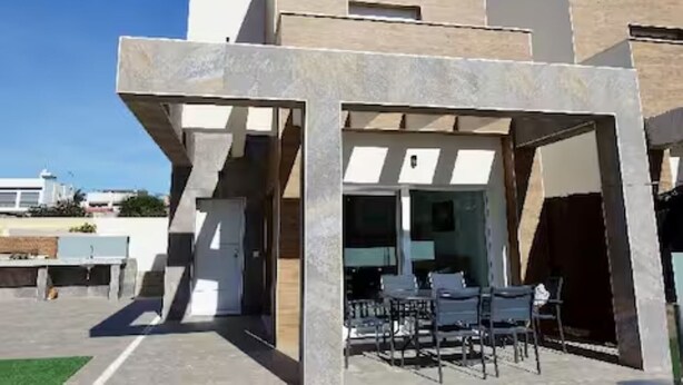 A modern building with a covered patio area featuring outdoor seating.