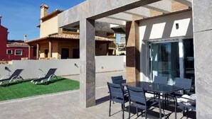 A modern outdoor patio with a glass door, a table, and chairs.