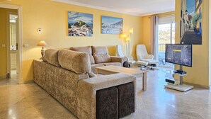 A living room with a sofa, armchairs, a coffee table, and a TV.