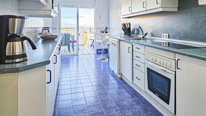 A modern kitchen with white cabinets, a stainless steel range hood, and a blue-tiled floor.