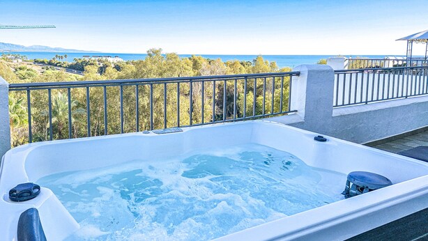 A hot tub with a view of the ocean and trees.