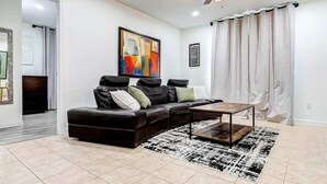 Una sala de estar moderna con un sofá modular, una mesa de centro y un cuadro abstracto grande en la pared.