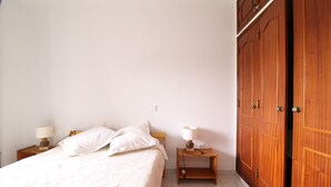Ein Schlafzimmer mit einem Bett, zwei Nachttischen, einem Schrank und einem Kleiderschrank.