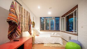 Een slaapkamer met een bed, bureau, stoel, raam en een radiator.