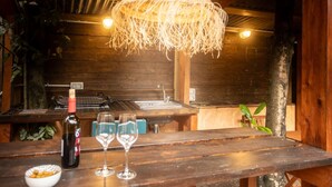 Un interior rústico de madera con una zona de bar que incluye una botella de vino y dos copas.