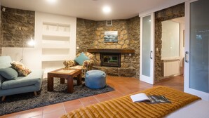 Una sala de estar acogedora con una pared de piedra, chimenea, sofá, mesa de centro y alfombra.