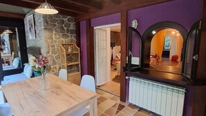 A cozy room with a wooden table, chairs, a stone wall, and a purple wall. - Inspiring Loft in the forest. Armonía Natura House (Camargo)