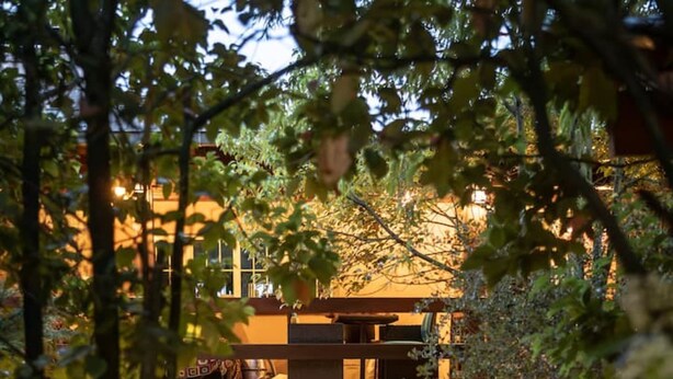 A rustic wooden structure with a stone pathway leading to a seating area, surrounded by trees and illuminated by lanterns. - Inspiring Loft in the forest. Armonía Natura House (Camargo)