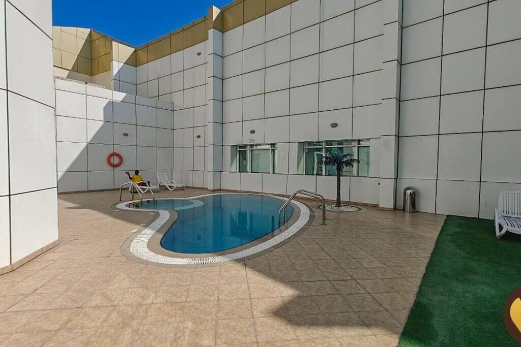 A swimming pool area with tiled walls, a pool, and a few lounge chairs.