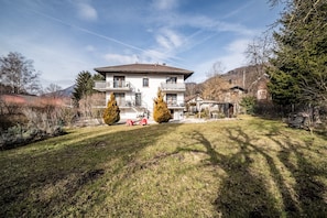 Ein zweistöckiges Haus mit Balkon, einem gepflegten Rasen und Bergblick.