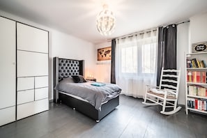 Ein modernes Schlafzimmer mit Bett, Kleiderschrank, Schaukelstuhl und Bücherregal.