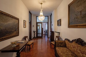 A hallway with a chandelier, a dining table with chairs, a sofa, and framed artwork on the walls. - Villa Gabri 1 e 2 (Arona)