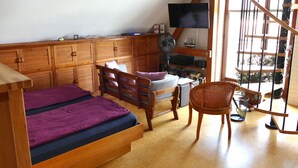 Un dormitorio con cama, una silla, un televisor y una ventana con vistas.