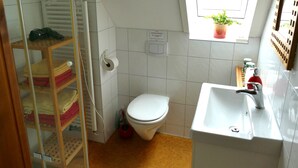 Un baño pequeño con inodoro, lavabo y una ventana con una planta.
