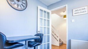 A room with a bar area, a clock, a door, and a sign that says "THIS IS OUR HAPPY PLACE". - Gellionen - 2 Bedroom House - Clydach (Swansea)