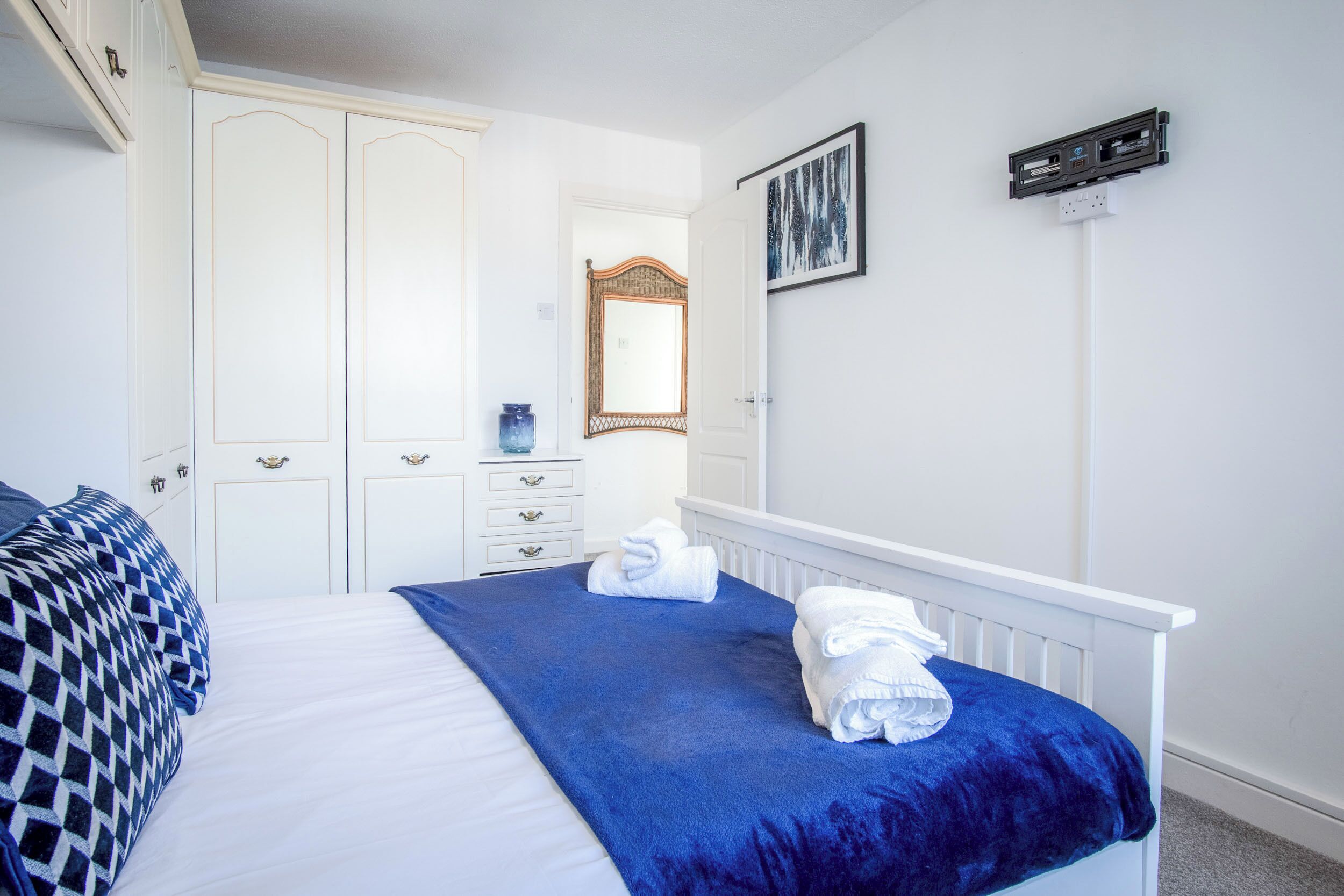 A bedroom with a bed, a blue blanket, and two white towels.