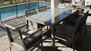 Un patio cubierto con piscina, muebles de exterior y vista al jardín trasero.