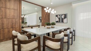 Un comedor moderno con una mesa rectangular grande, varias sillas, una araña y un espejo amplio.