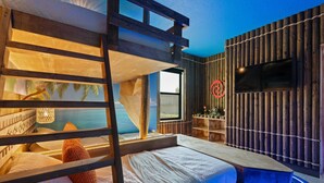 Ein Schlafraum mit Etagenbetten und Meerblick, einer Holzwand mit Fernseher und einer kleinen Schreibtischzeile.