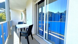 Ein Balkon mit Tisch und Stühlen, eine Schiebetür und Blick ins Freie.