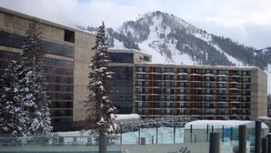 Ein Hotel mit Schwimmbad, umgeben von schneebedeckten Bergen.