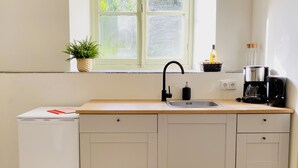 Een kleine keuken met een spoelbak, koffiezetapparaat en een compacte koelkast.