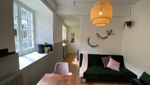 A modern living room with a wooden table, a green sofa, and a large window.