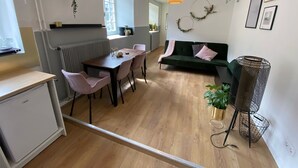 A modern kitchen with a dining area, a green sofa, and a hanging plant.