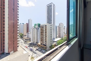 A high-rise building with multiple floors, a parking area in front, and a view of other buildings in the distance. - Charming Studio Near the Airport Gln0805 (Recife)