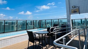 A rooftop terrace with a pool, chairs, and a city view. - Charming Studio Near the Airport Gln0805 (Recife)