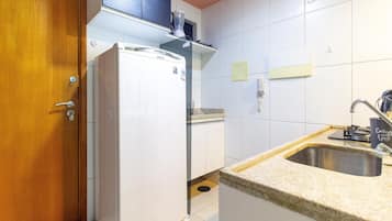 Una cocina compacta con refrigerador, lavamanos y puerta de madera.