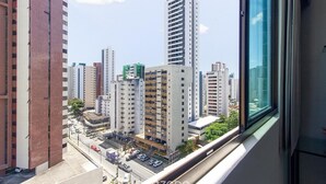 A high-rise building with multiple floors, a parking area in front, and a view of other buildings in the distance. - Charming Studio Near the Airport Gln0805 (Recife)