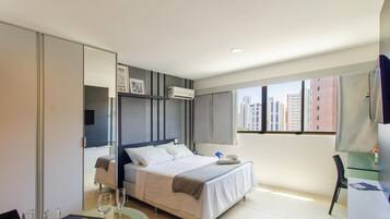 Quarto de hotel moderno com uma cama, uma escrivaninha e vista para edifícios altos.