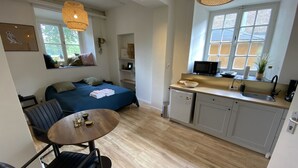 Een compacte leefruimte met een bed, een eettafel, een kitchenette en een raam met uitzicht.