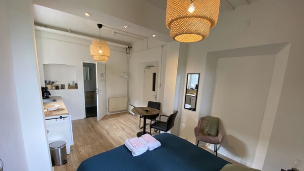 Een moderne hotelkamer met een groot bed, een eethoek en een kitchenette.