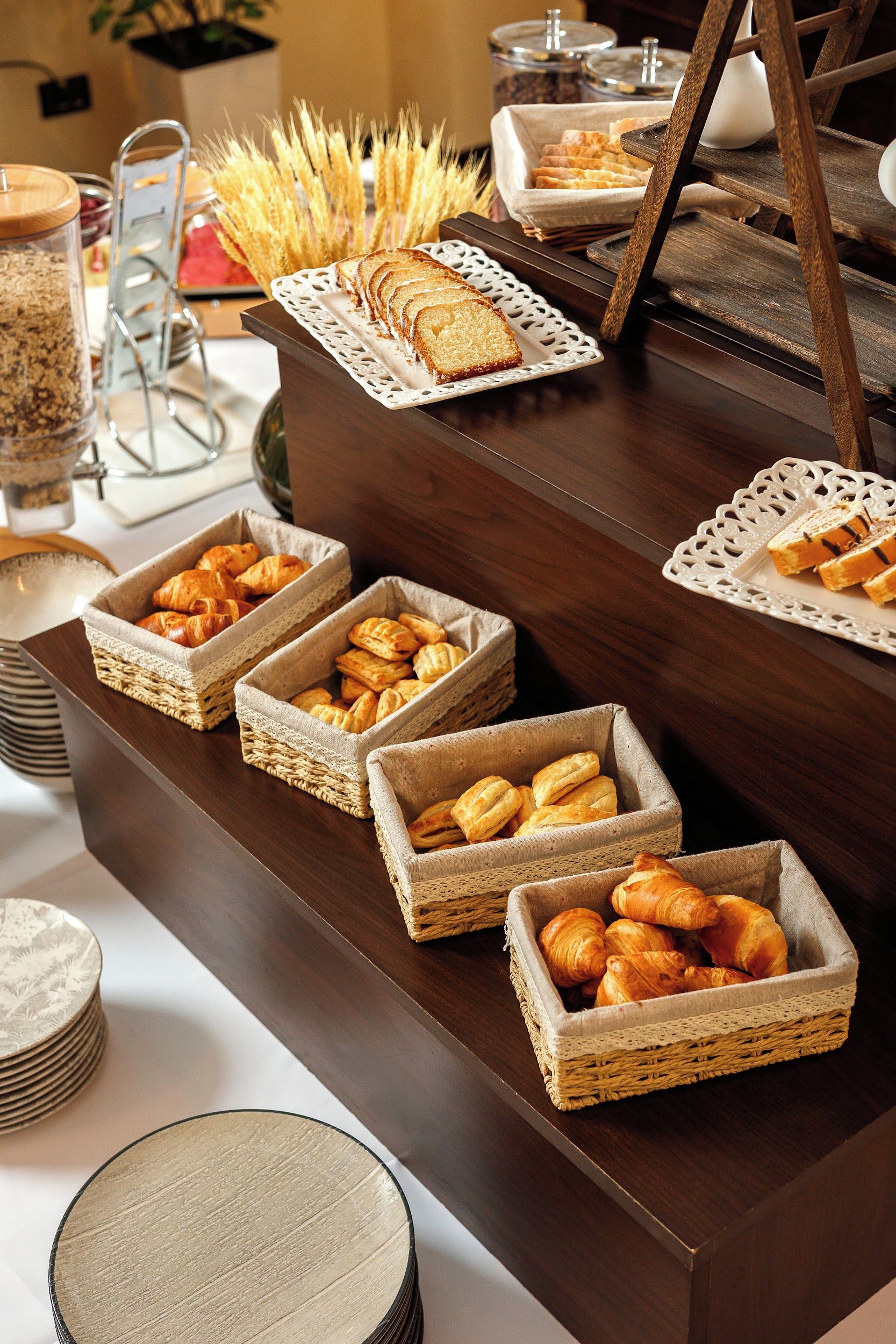 Una mesa de buffet con pan, pasteles y un centro de mesa decorativo.