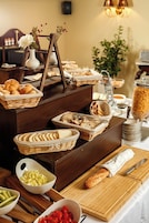 Montaje de bufé con diversos alimentos, como pan, verduras y una jarrón decorativo con flores.