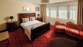 A hotel room with a large bed, a sofa, a desk, and a chair.
