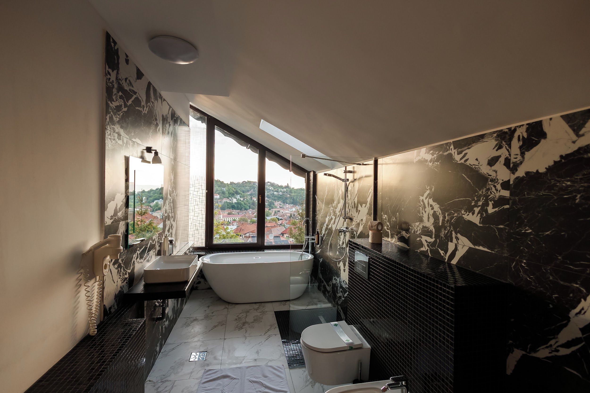 A modern bathroom with a bathtub, a large window, and a view of a cityscape.