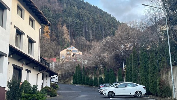 Una calle con coches aparcados, un edificio con un letrero y una montaña al fondo.