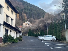 Una calle con coches aparcados, un edificio con un letrero y una montaña al fondo.