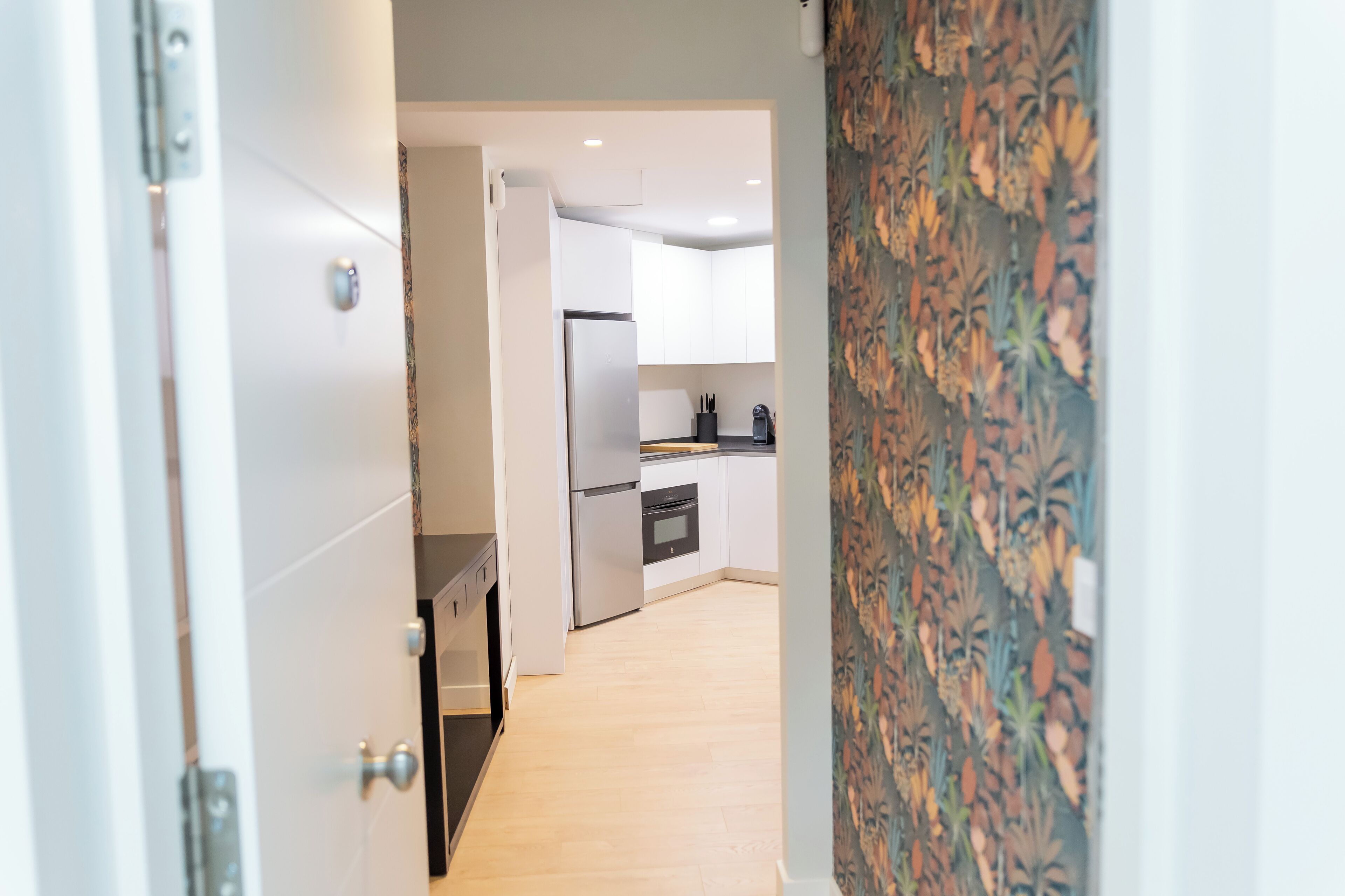 Een moderne keuken met witte kasten, een roestvrijstalen koelkast en een houten aanrecht.