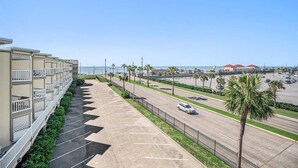 A hotel with a parking lot and a view of the beach. - Ocean View Top Floor - 2 Pools - Hot Tub - GYM - Tennis (Galveston)