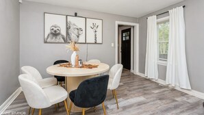 A dining area with a round table, four chairs, and wall art. - Cozy Winter Escape - Hot Tub, Game Room, Fireplace, Sleeps 6 (Waterbury)