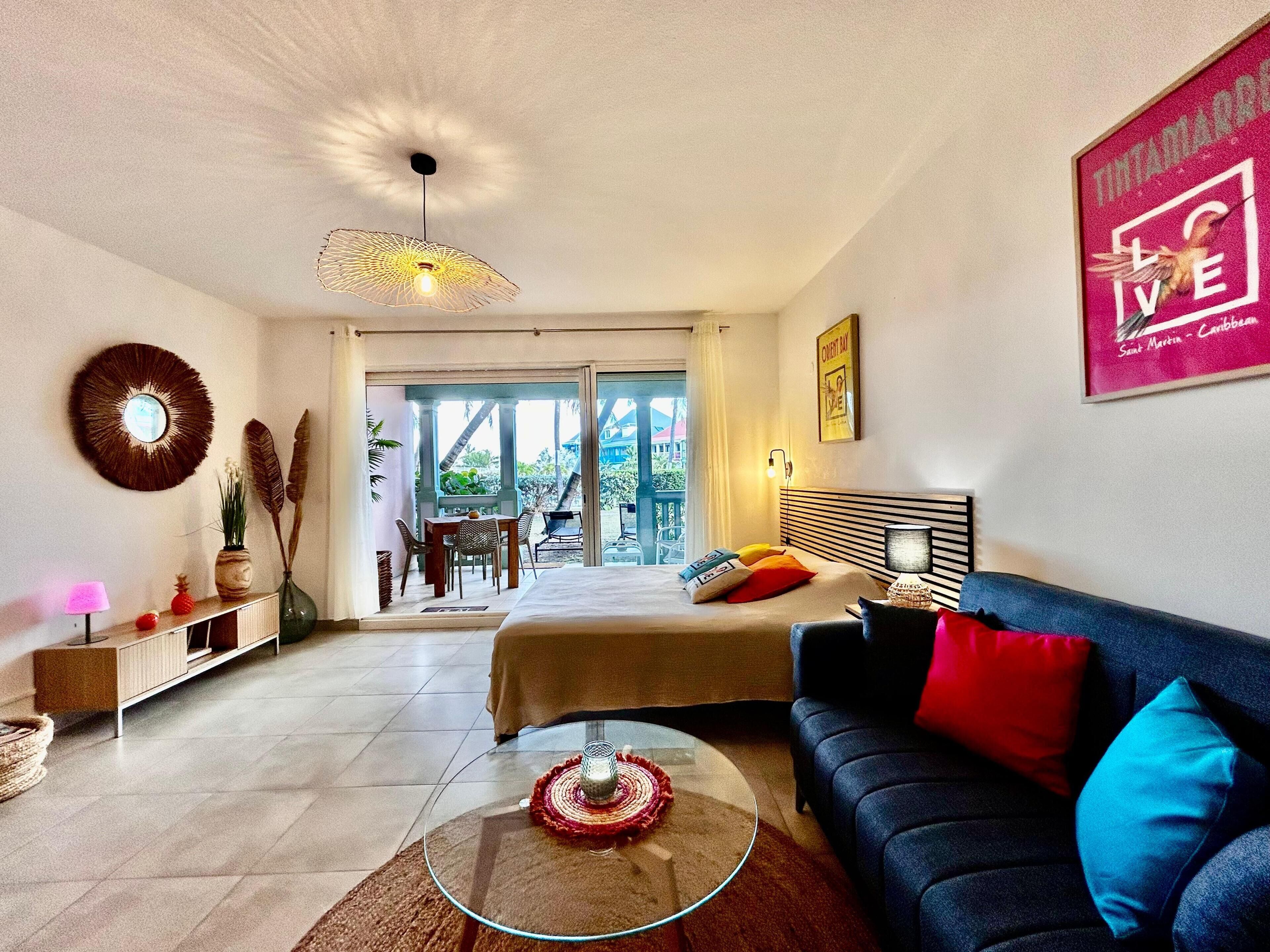Ein modernes Hotelzimmer mit einem Bett, einer Couch, einem Glastisch, einem Essbereich mit Stühlen und Blick nach draußen.