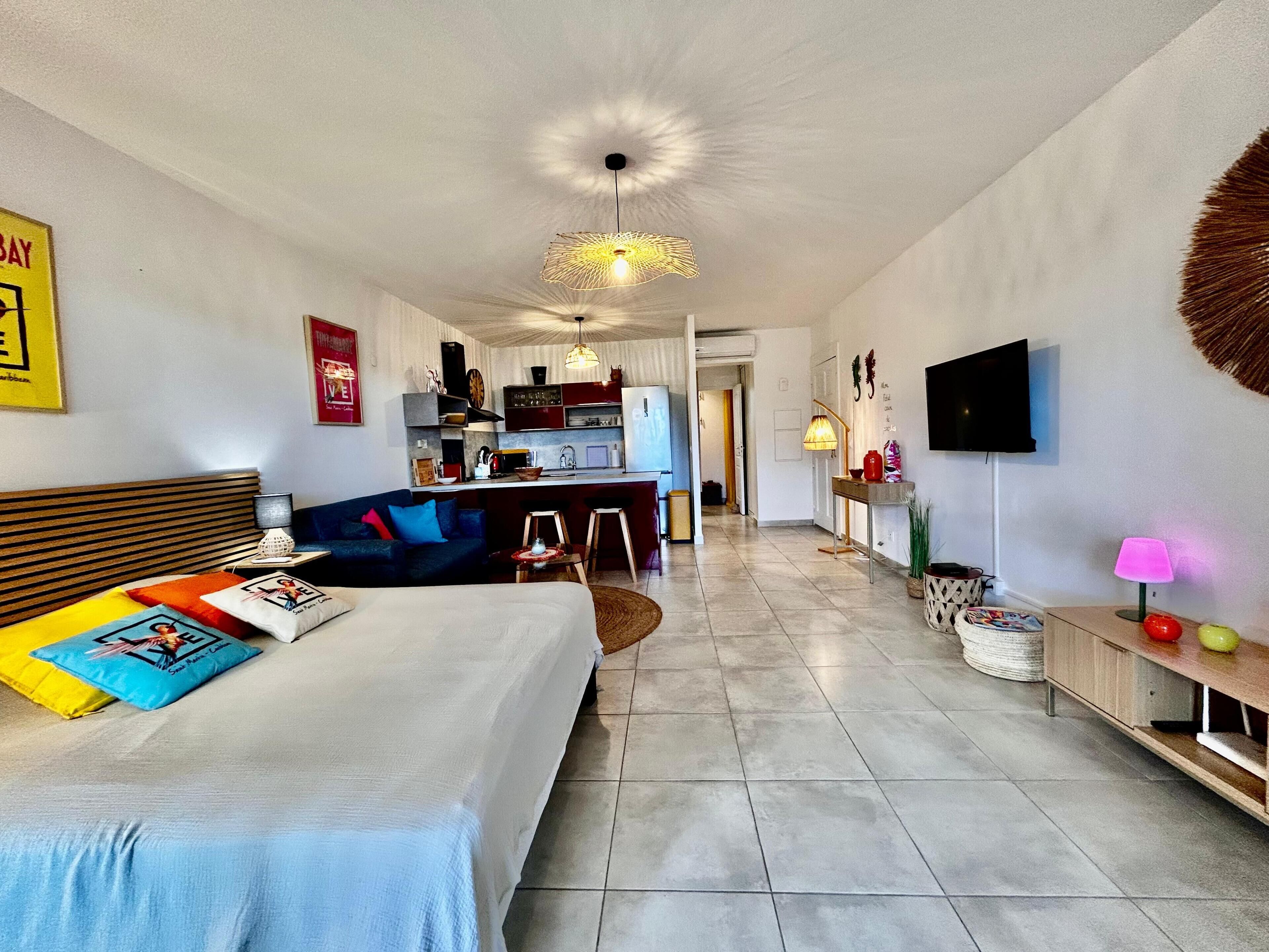 Ein modernes Wohnzimmer mit Sofa, Bett, Essbereich und Küche.